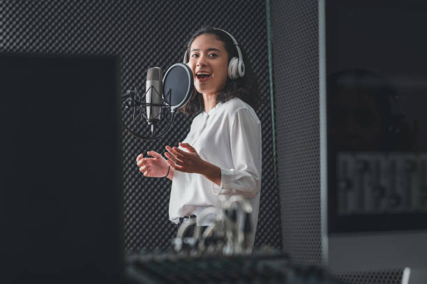 istock Asian female singer with a passion for music and microphone. While playing her guitar in a professional studio. Music concept, sound recording concept. 1300523098