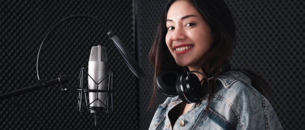 istock Asian female singer with a passion for music and microphone. While playing her guitar in a professional studio. Music concept, sound recording concept. 1300523204