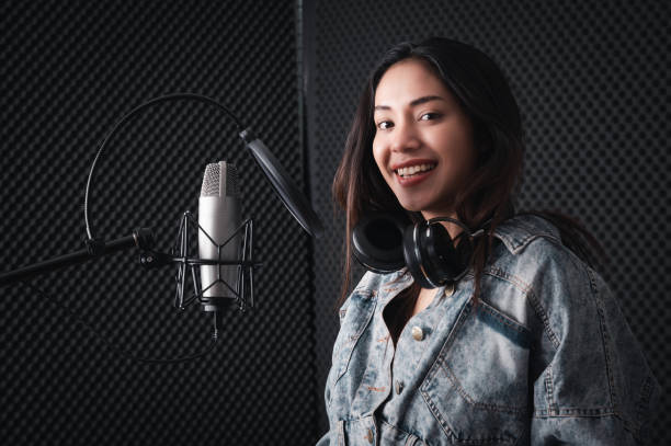 istock Asian female singer with a passion for music and microphone. While playing her guitar in a professional studio. Music concept, sound recording concept. 1300523459