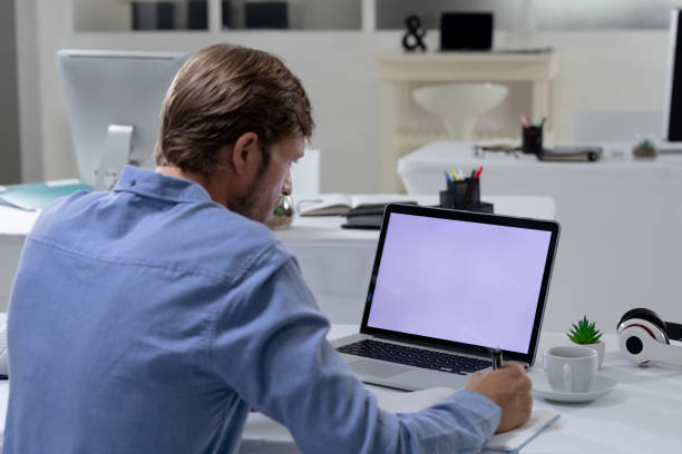 istock Caucasian businessman sitting at desk using laptop in an empty office 1300524404