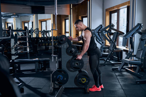 istock Young handsome man preparing equipment for weightlifting 1300527318