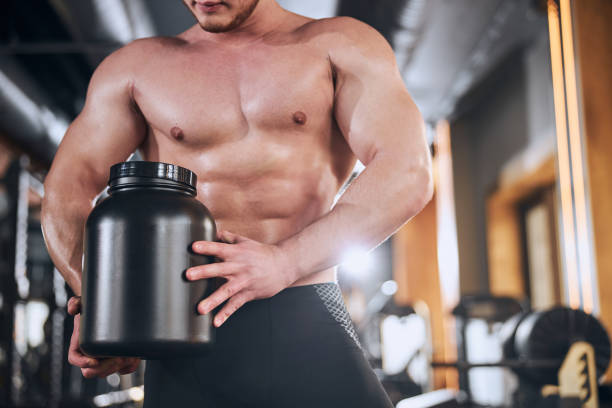 istock Strong sportsman is taking protein in gym 1300527404