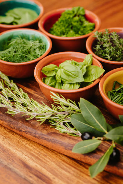 istock Herbs in bowls on a rustic wooden board with focus on the basil with copy space 1300528449