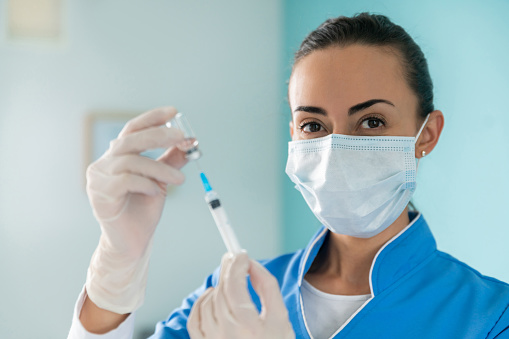 Portrait of a happy Latin American nurse preparing a COVID-19 vaccine at the hospital - pandemic protocol concepts