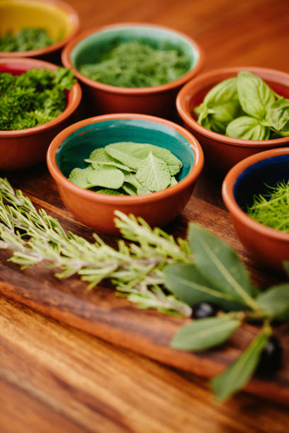 istock Herbs in bowls on a rustic wooden board with focus on the sage with copy space 1300529340