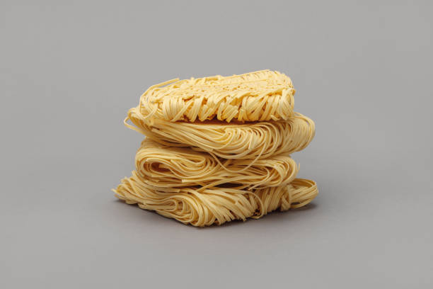 istock Raw strips of egg noodles on gray background. 1300529795