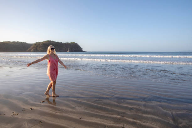istock Woman dances down sandy beach in the morning 1300532282