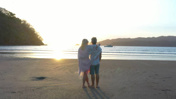 istock Mature couple walks down sandy beach in the morning 1300532380