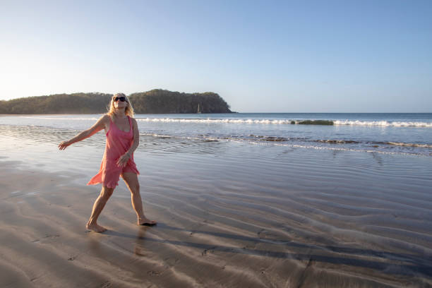 istock Woman dances down sandy beach in the morning 1300532676