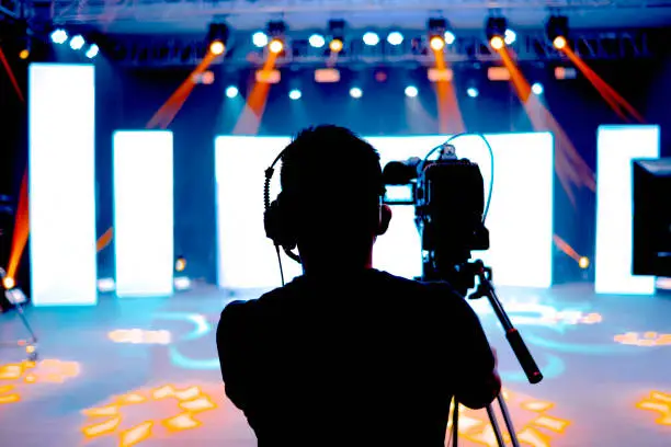 Photo of Professional cameraman - covering on event with a video, cameraman silhouette on live studio news, Selective focus