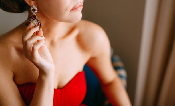 la femme dans une robe rouge touche sa boucle d’oreille - boucle doreille photos et images de collection