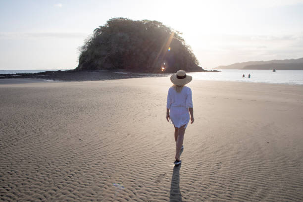 istock Woman walks down beach at low tide in the morning 1300533400