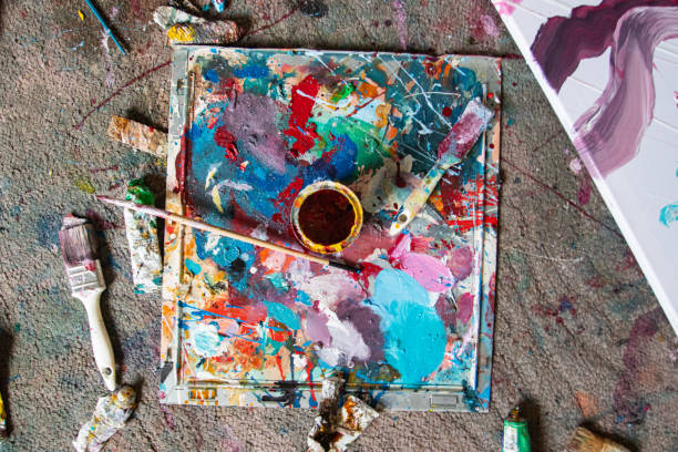 istock Dirty artist's palette and paintbrushes 1300538086