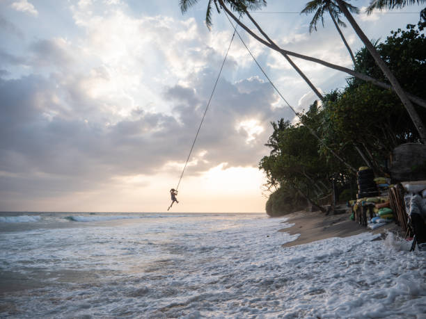 istock Woman plays on rope swing above sea 1300538326