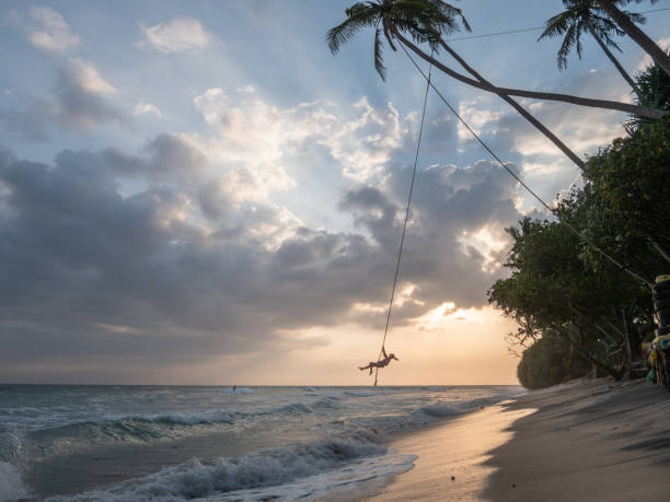 istock Woman plays on rope swing above sea 1300538355