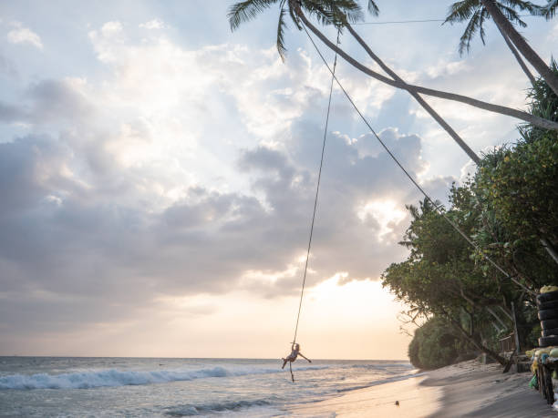 istock Woman plays on rope swing above sea 1300538371