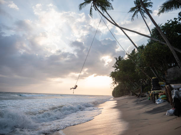 istock Woman plays on rope swing above sea 1300538376