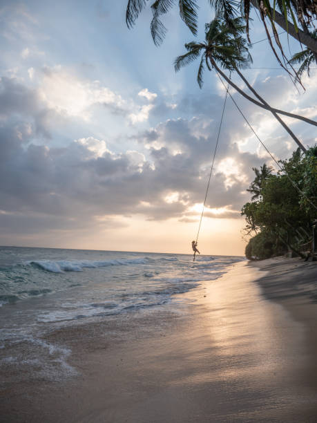 istock Woman plays on rope swing above sea 1300538387