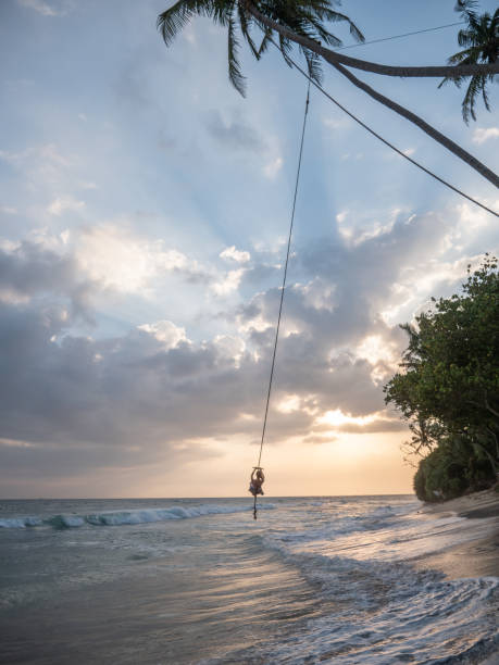 istock Woman plays on rope swing above sea 1300538389