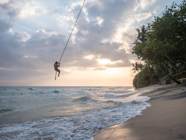 istock Man plays on rope swing above sea 1300538390