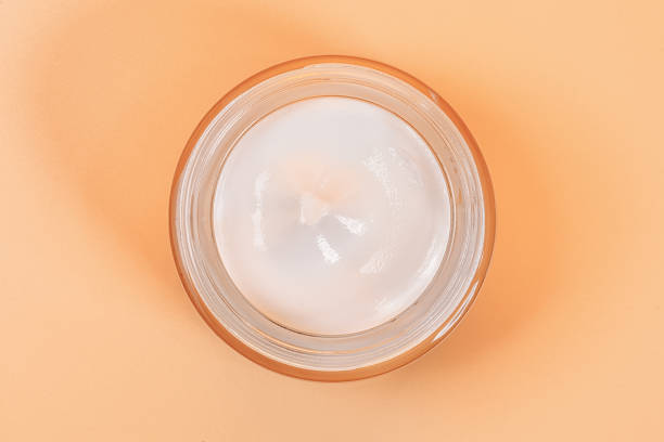 istock White moisturizer in a glass jar top view on beige 1300546829