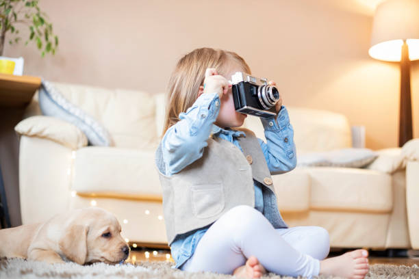 istock Little girl playing with analog retro camera at home 1300548129