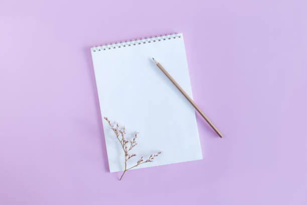istock Notebook with blank page and pencil on a violet pastel background. 1300553301