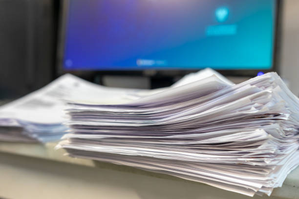 istock business office with many papers on the table in front of a personal computer with the screen illuminated in blue 1300555878