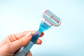 Women razor in hand isolated on a blue background. Close-up. Beauty concept.