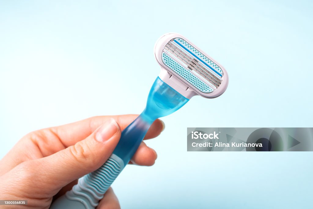 Women razor in hand isolated on a blue background. Close-up. Beauty concept. Women razor in hand isolated on a blue background. Close-up. Beauty concept Razor Stock Photo