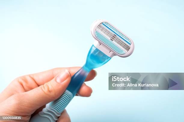 Women Razor In Hand Isolated On A Blue Background Closeup Beauty Concept Stock Photo - Download Image Now