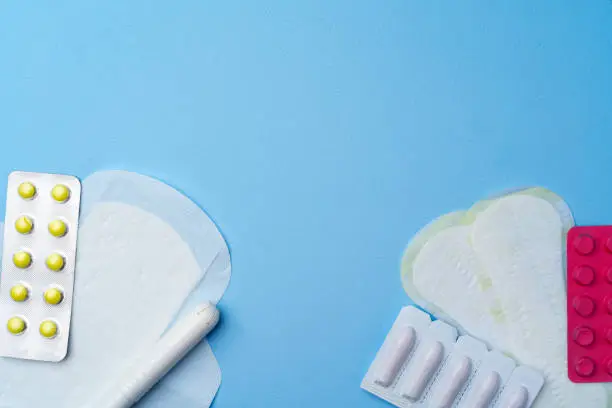 Photo of Contraceptive pills, hygienic pads and tampons on blue background