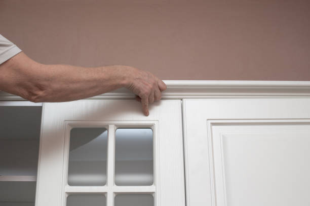 istock Furniture assembly. The man assembles the kitchen set, attaches the cornice to the upper cabinets 1300560900