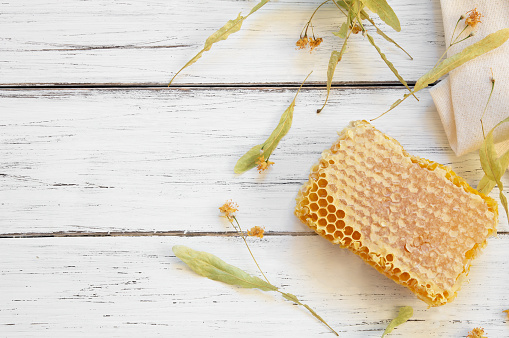 Linden honey concept, honeycomb with linden flowers on white wooden table, healthy food
