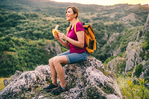 Young cheerful woman hiker enjoying a snack break
