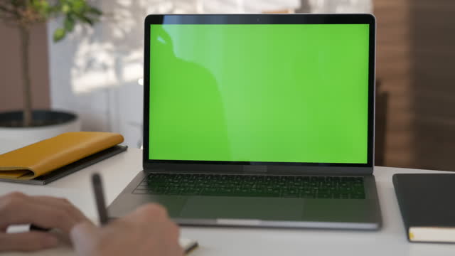 Girl looking at green screen laptop computer in living room watching video