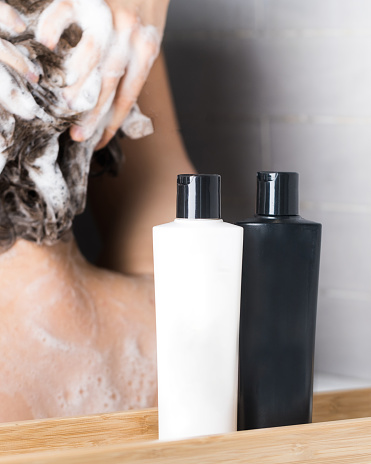 Shampoo, hair rinse is poured from a black tube into a woman's hand. An empty tube with a place for the logo. High quality photo