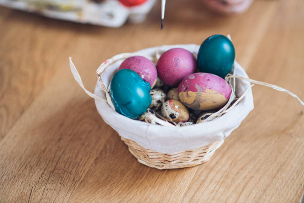 Beautiful décor for Easter. Basket with colorful eggs. There are multi colored eggs-purple, green, small one and bigger ones.