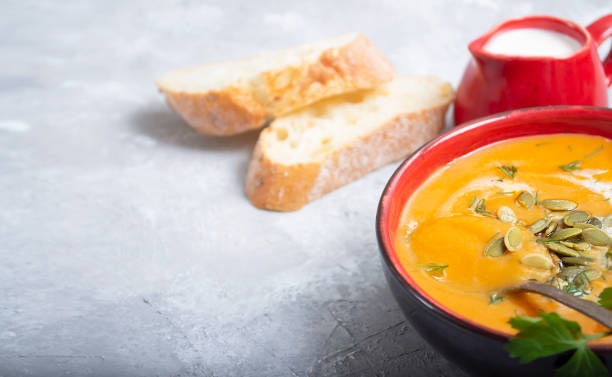 istock Pumpkin cream soup with croutons and cream on gray concrete background with copy space 1300566372