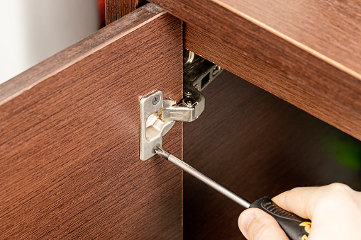handyman assembling cabinet loop hinge. repair furniture concept. door fixing.