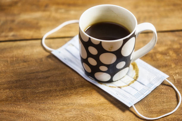 istock Coffee cup resting on a surgical mask with stains during the Covid-19 pandemic 1300569432