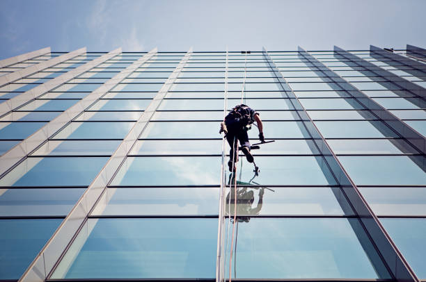 el limpiador de ventanas está trabajando en la fachada del edificio de oficinas - cleaning window window washer built structure fotografías e imágenes de stock