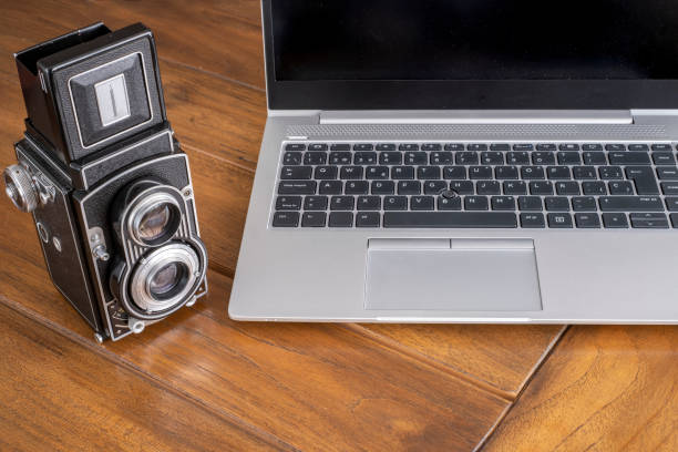 modern laptop computer next to an old twin lens camera