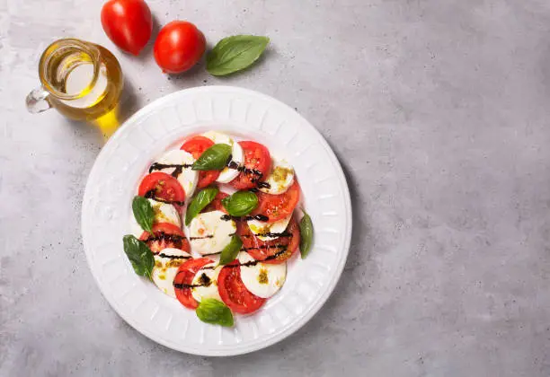 Caprese salad. Italian famous salad with fresh tomatoes, mozzarella cheese and basil, top view with copy space