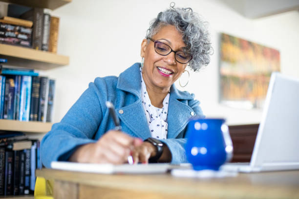 Mature Black Woman Working from Home A beautiful mature black woman with gray hair working from home. beautiful older black woman stock pictures, royalty-free photos & images