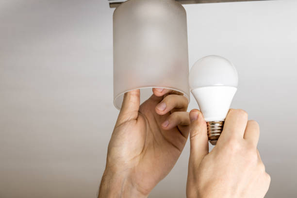 istock handyman replacing light bulb at wall lamp. changing light equipment for more energy efficient concept. electricity save conceptual 1300581164