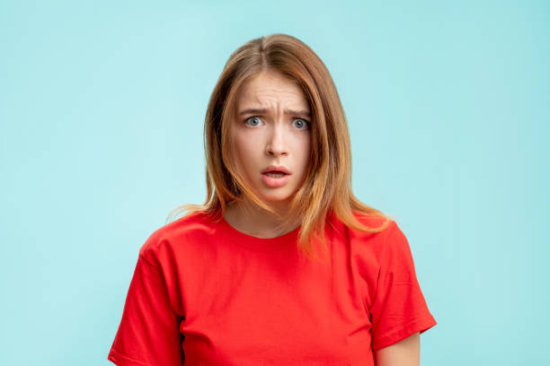 overwhelmed woman portrait wtf reaction shocked Overwhelmed woman portrait. Wtf reaction. Shocked lady in red t-shirt looking at camera questioning annoyed isolated on blue copy space background. Disappointment fear. wtf stock pictures, royalty-free photos & images