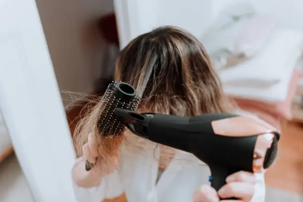 woman drying her hair with dryer
