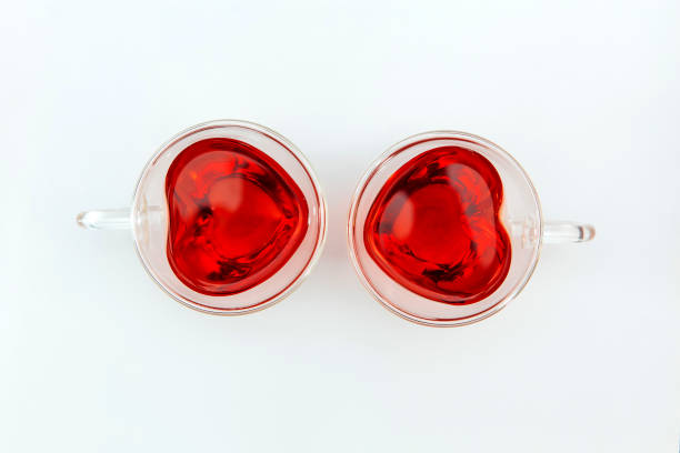 istock Two transparent heart-shaped cups with tea on the white background. Top view. 1300589846