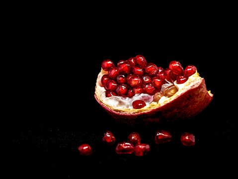 slice the pomegranate with red grains on a black background, a narrow focus area